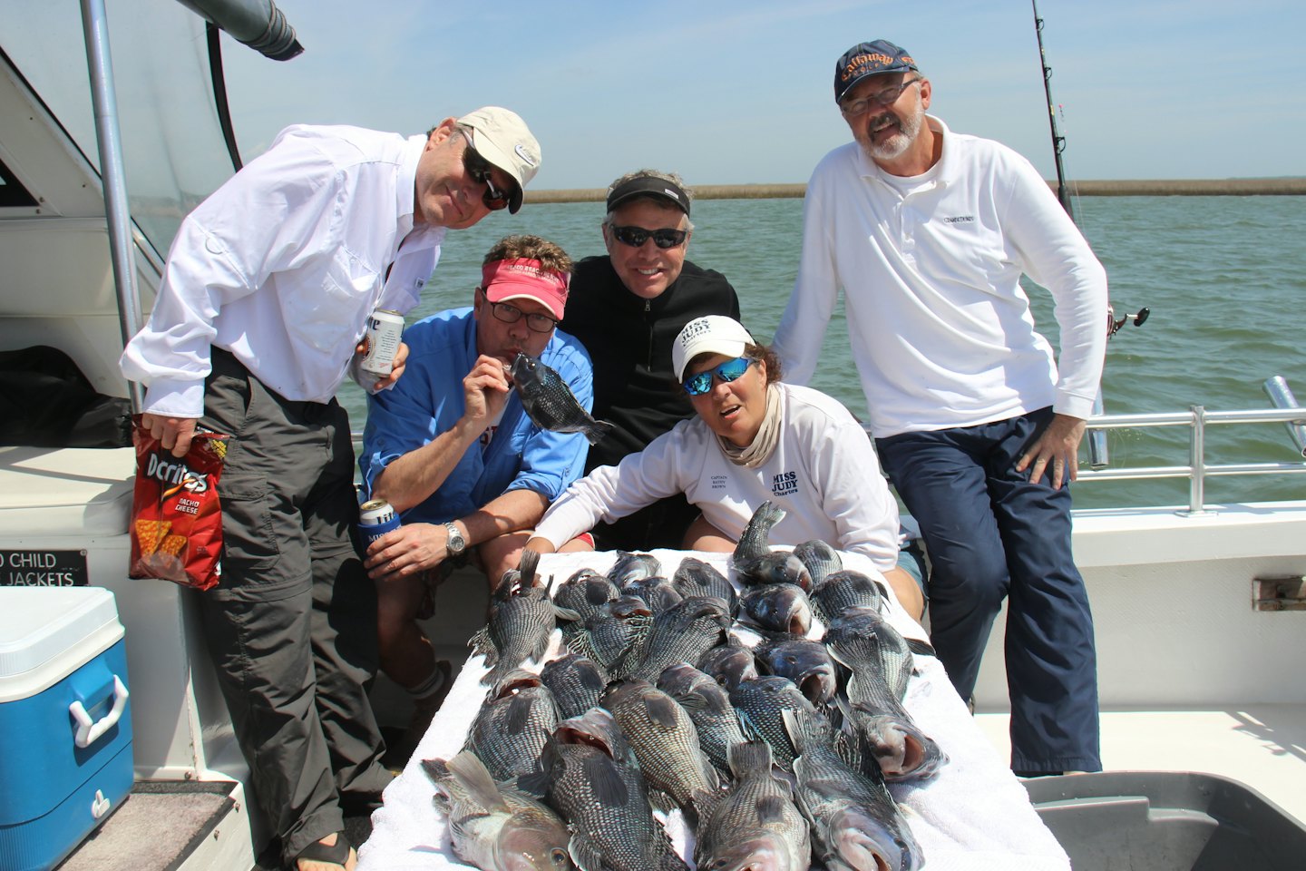 Five smiling people on a boat deck with their large fish catch.